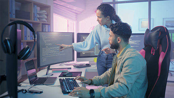 GaussDB noSQL A woman and a man in front of a screen, the woman points to a monitor